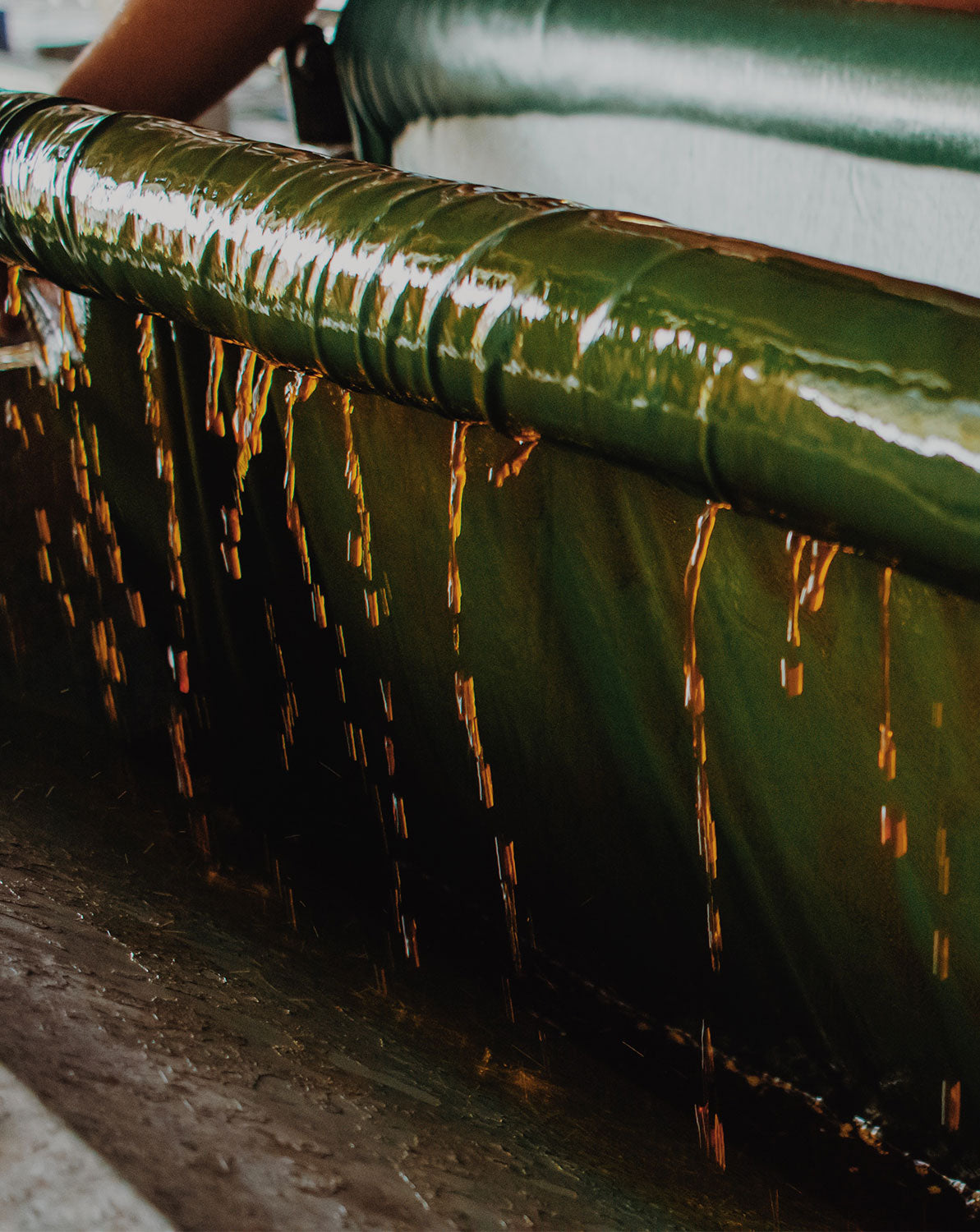 Close-up of a fabric roll that is dripping fabric-dye in the process of hand-dying sustainable fashion fabrics.