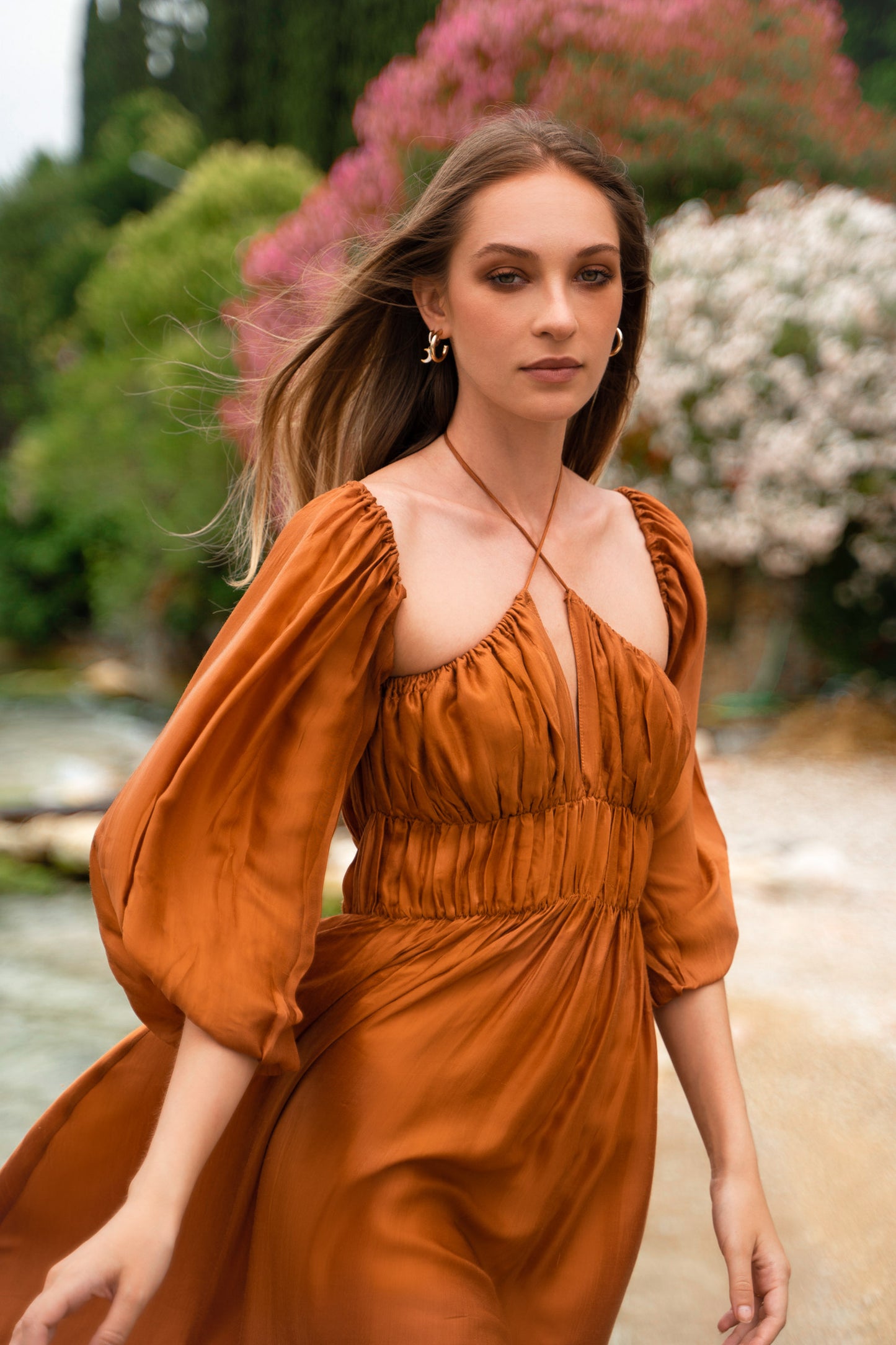 An orange satin maxi dress, with puff sleeves and shirred bust.