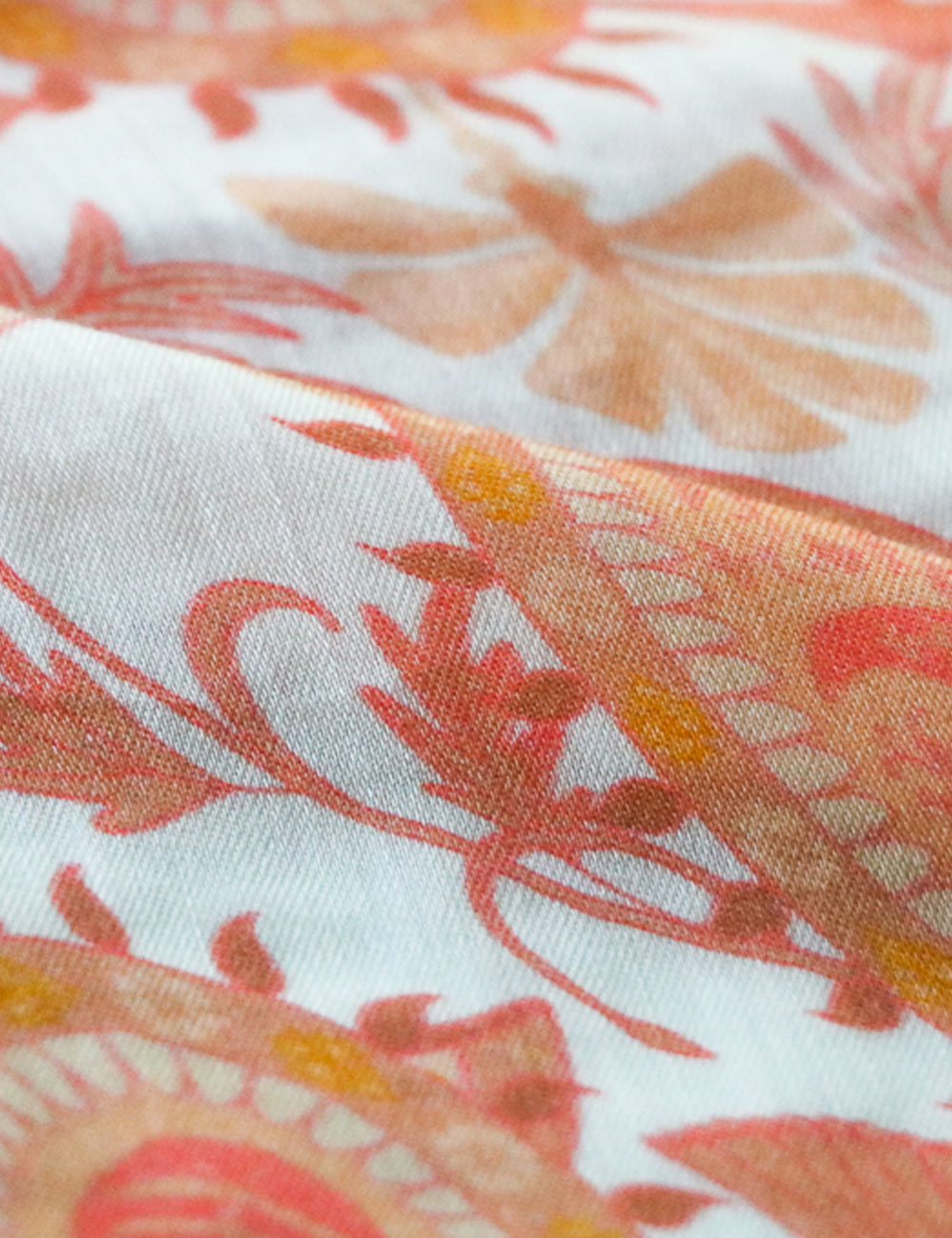 Close-up photograph of bemberg satin fabric, printed in orange paisley pattern.