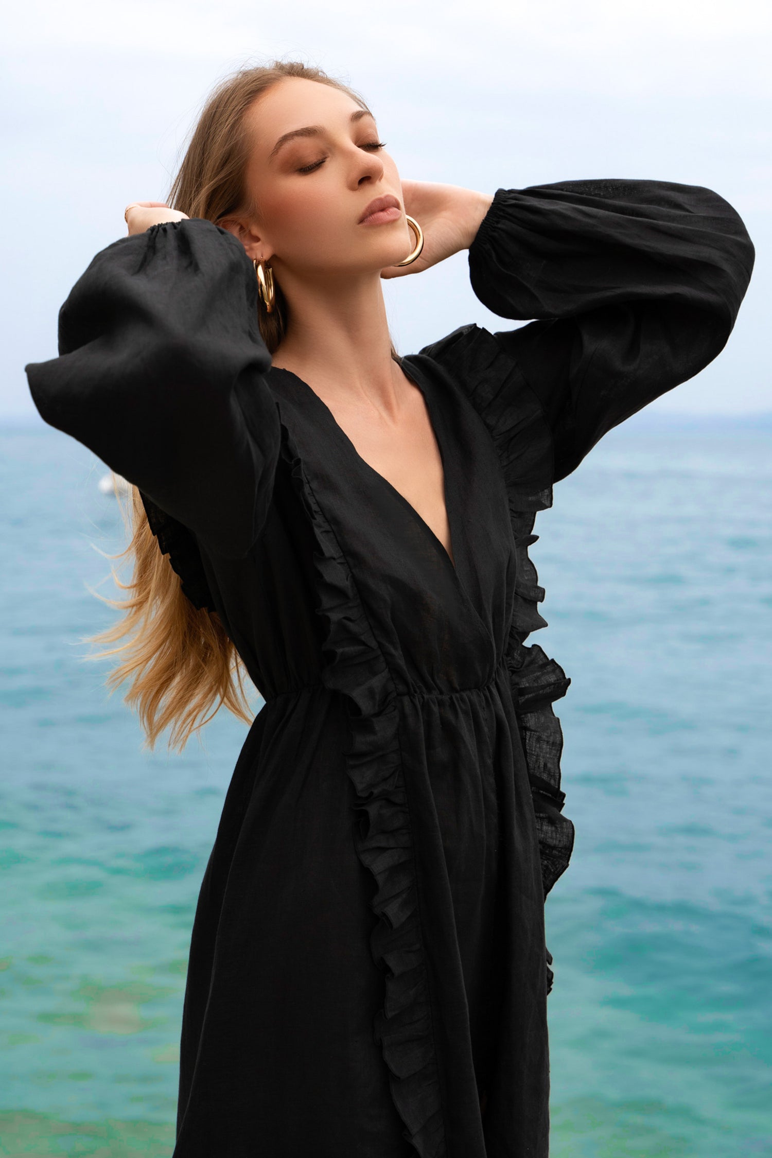 A black linen maxi dress, with long puff sleeves, ruffles and open back with ties.