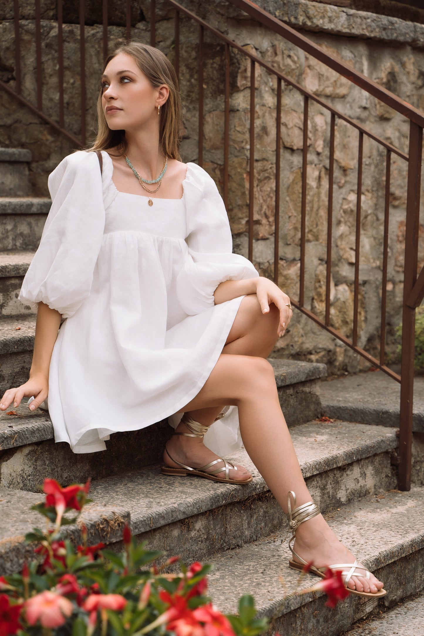 A white linen mini dress, with puff sleeves, straight neckline and open back with bow ties.