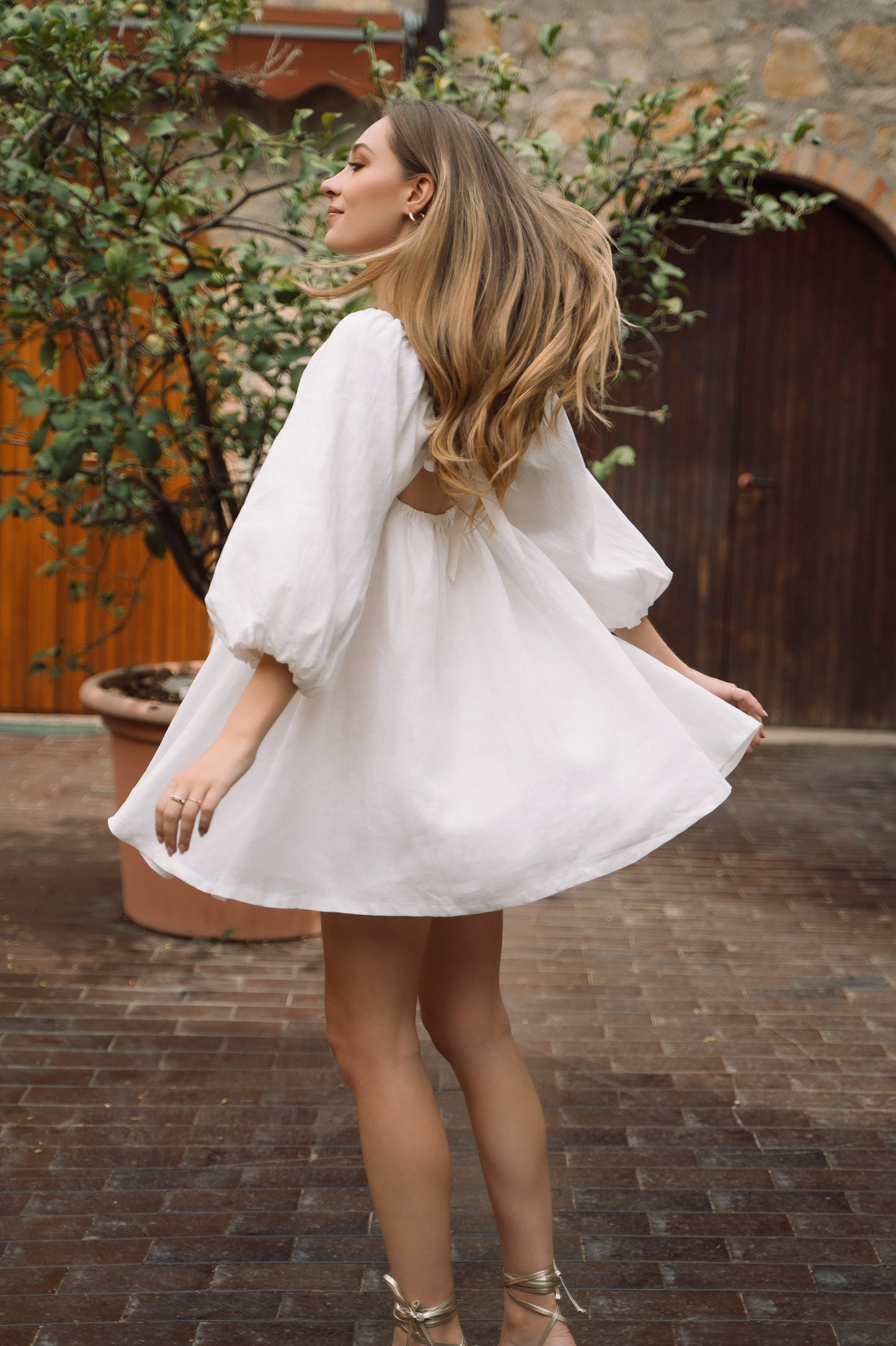 A white sustainable linen Fiamma Studio mini dress, with puff sleeves and voluminous skirt.