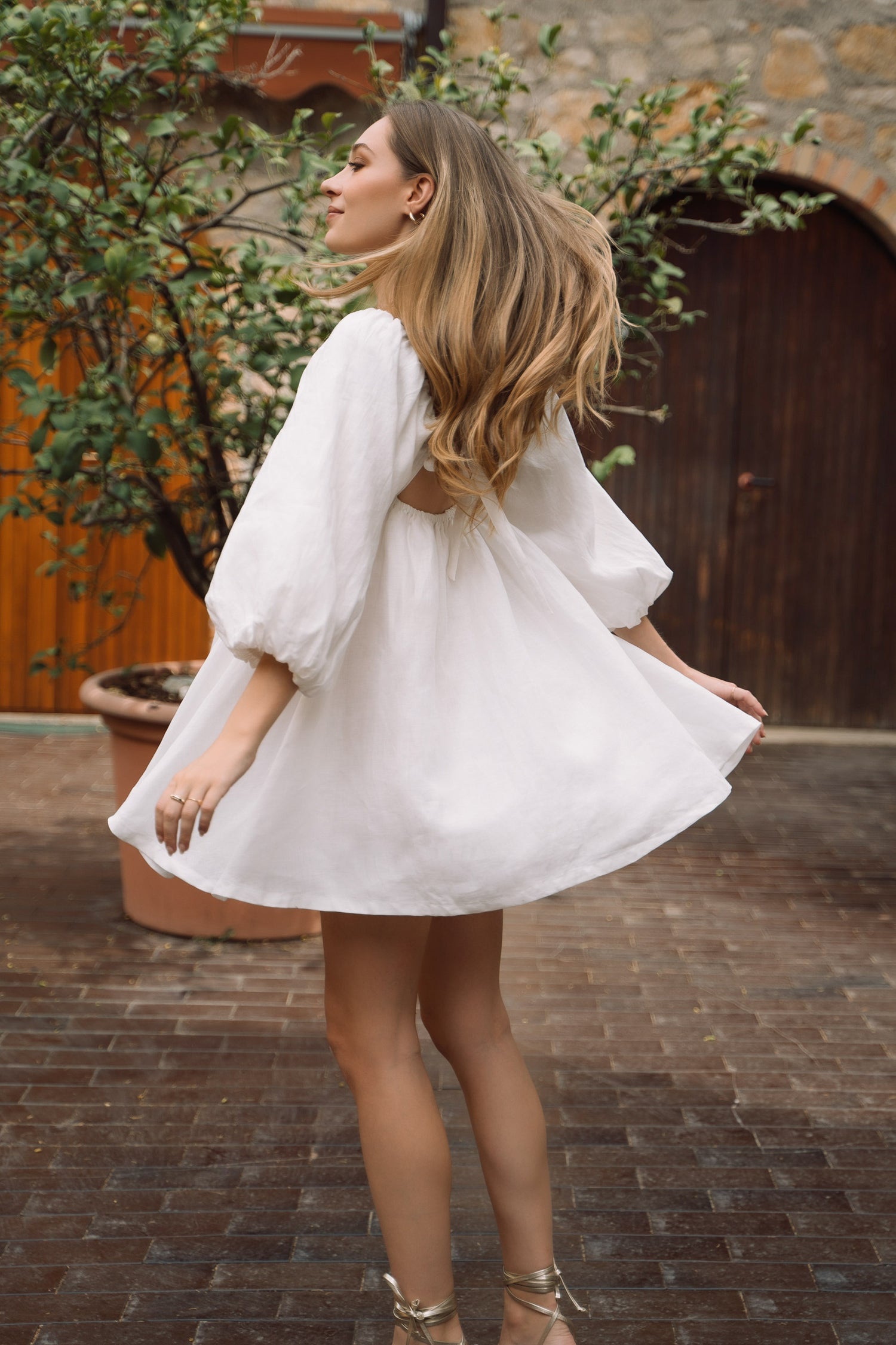 A white sustainable linen Fiamma Studio mini dress, with puff sleeves and voluminous skirt.