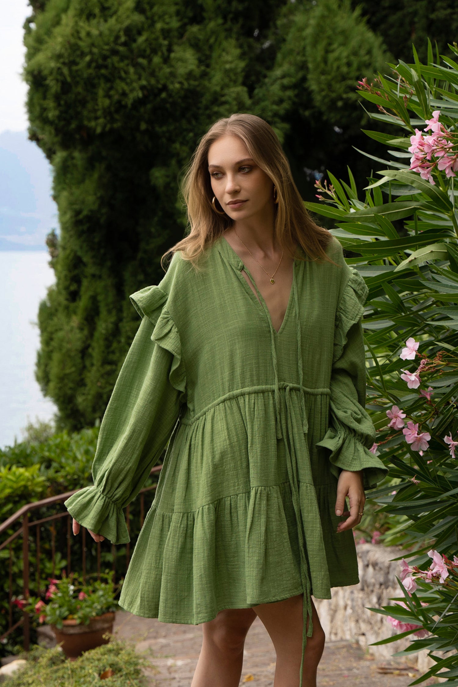 A green cotton Fiamma Studio dress, with long puff sleeves, waist ties and tiered skirt.