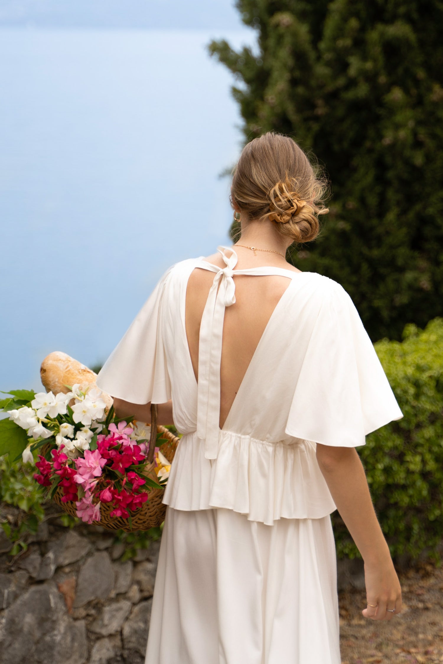 A white bamboo Fiamma Studio midi dress, with waist frill and open back with bow tie.