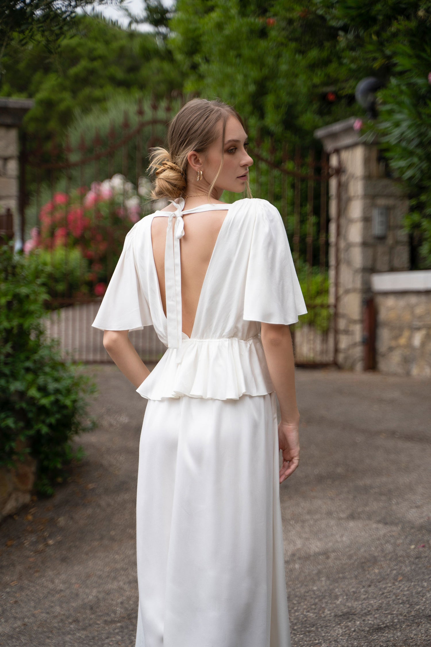 A white bamboo Fiamma Studio midi dress, with waist frill and open back with bow tie.