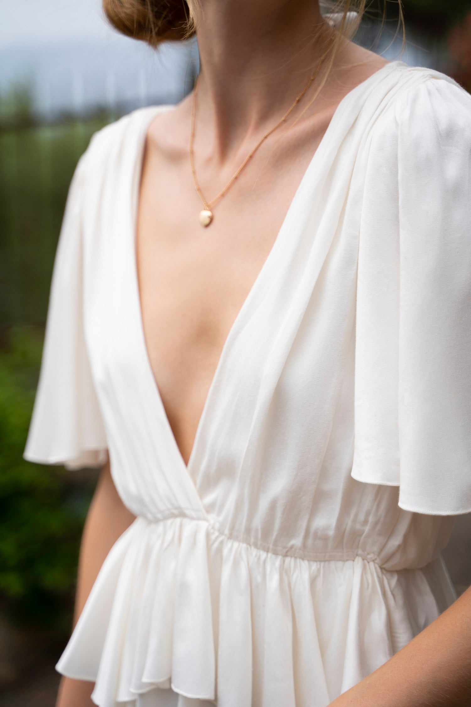 A white bamboo Fiamma Studio midi dress, v-neckline, waist frills and flowy sleeves.