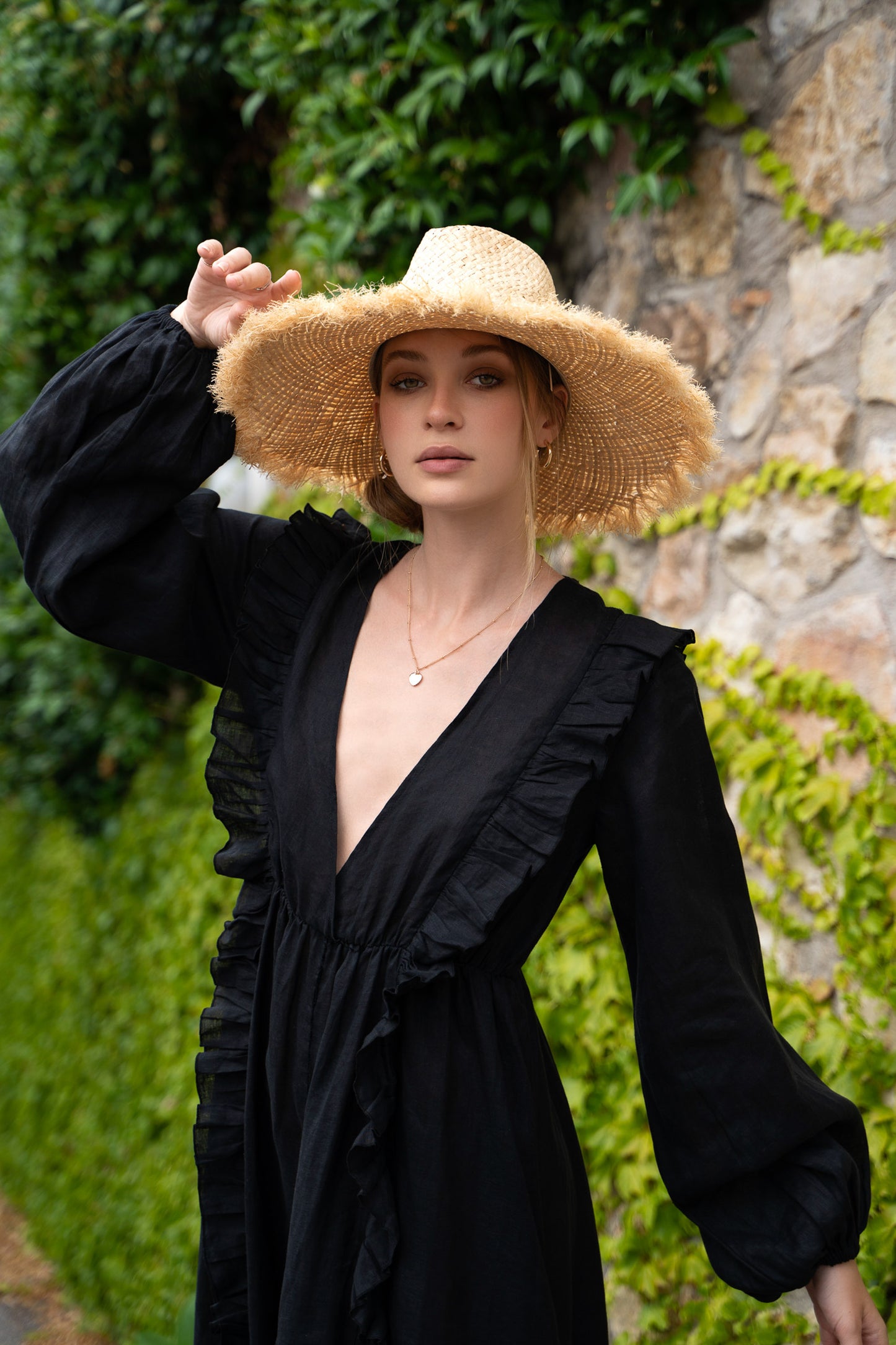 Close-up of black linen Fiamma Studio maxi dress, with long puff sleeves, v neckline and skirt with slit.