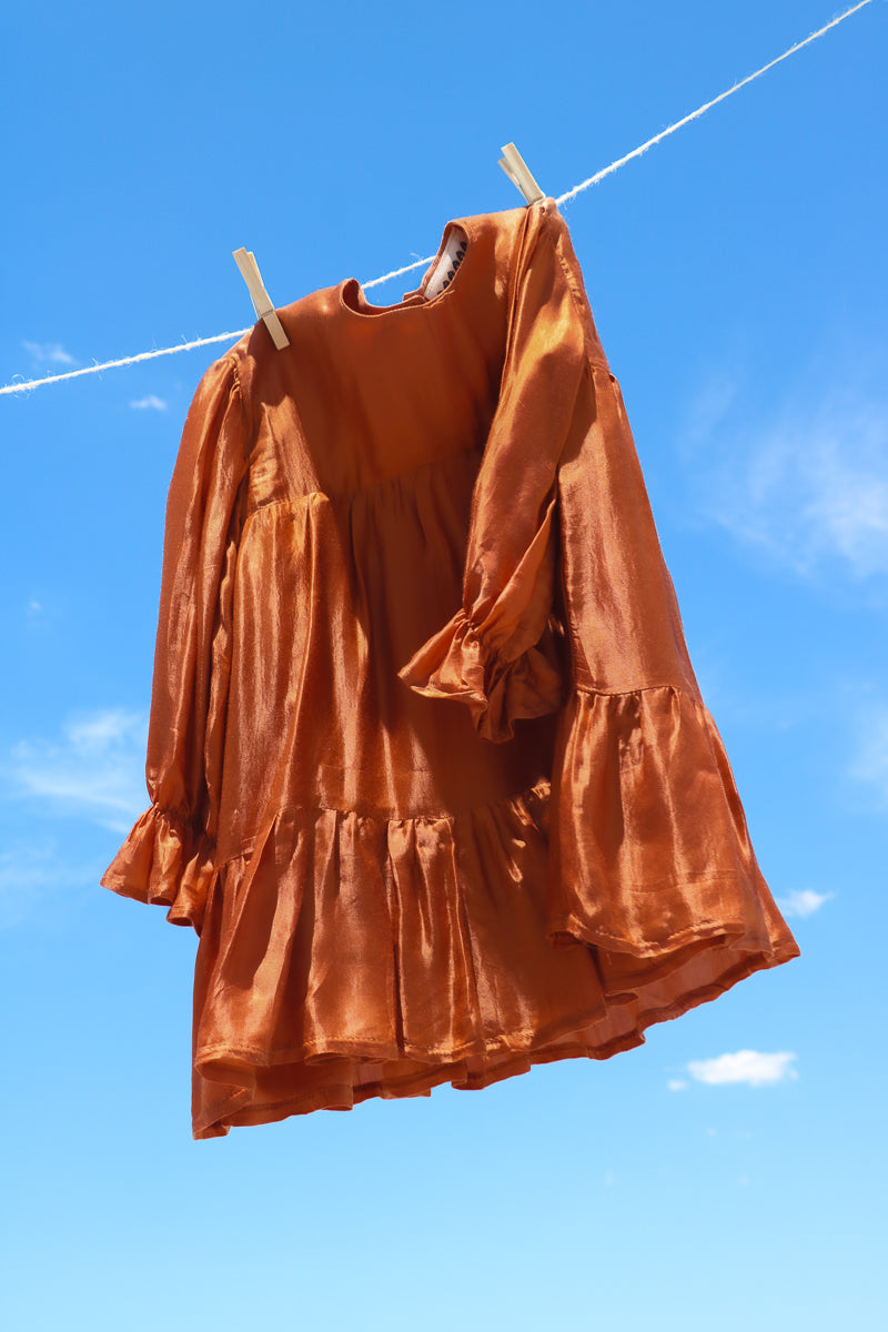 Orange girls dress, with long sleeves, frilled wrist cuffs and tiered skirt.