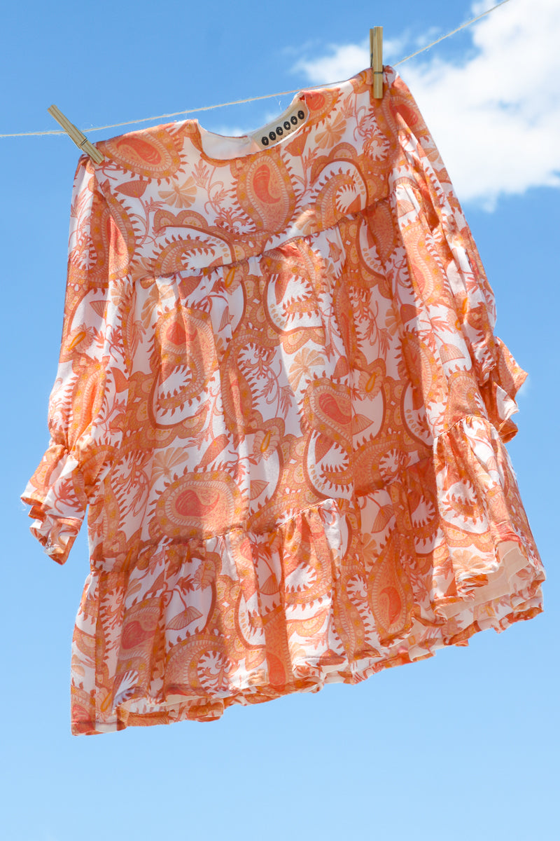 Full figure long sleeves dress for girls, in bemberg cupro shiny fabric, printed with orange paisleys pattern.