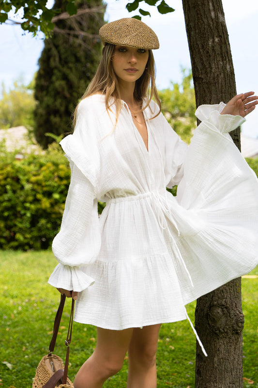 Flowy white cotton dress with long puff sleeves, sustainable fabric and tiered skirt.